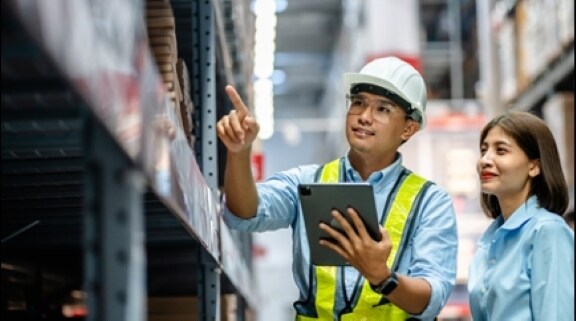 Warehouse staff reviewing inventory using a tablet.