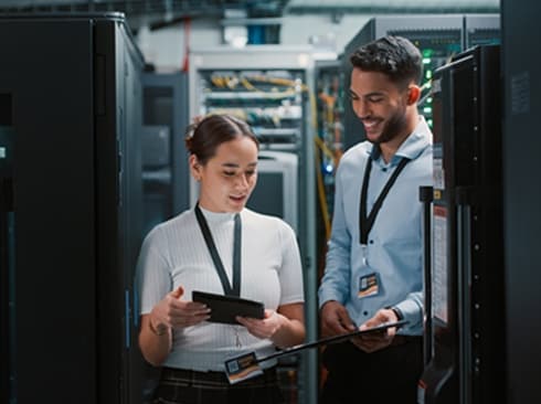 Two professionals reviewing data center equipment using digital devices.