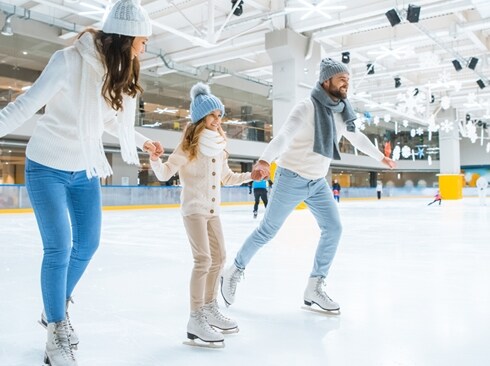 People skating together at an indoor ice rink.