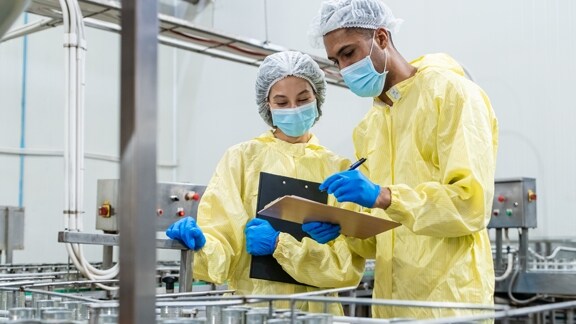 Workers inspecting production equipment in a food facility